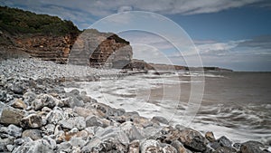 South Wales coastline, showing the water lapping against the rocky shore, flanked by high cliff.