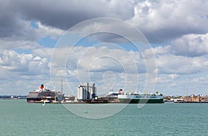 Southampton Docks with big cruise ship and cargo vessel on calm summer day with fine weather blue sky and white clouds