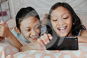 Southeast Asian ethnicity teenage girls laughing together having fun viewing information from smartphone