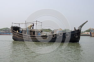 Southeast Asian fisher boat running through a river. Old wooden fishing trawler side view. Beautiful rural life and waterway