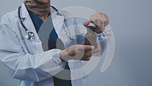 Southeast Asian medical doctor holding a bottle of pills, smiling isolated white background