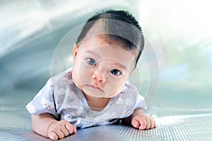 Southeast Asian new born is creeping on the floor. Newborn is wearing gray shirt. Baby is South East Asian. Kid is cute.