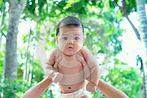 Southeast Asian new born isn`t wearing shirt. South East Asian newborn is 3 months old. Mother`s holding Infant with hands.