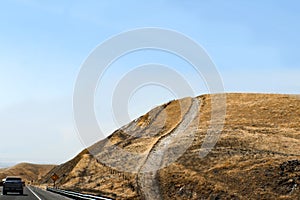 Southeastern California highway with road going almost straight up a hill covered with brown grass that has obviously been burned