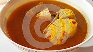 Southern thai spicy sour yellow curry with young papaya and sea bass on white background.