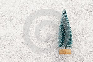 Souvenir Christmas tree on white snow. Background for the design of cards on the theme of the winter holidays. Copy space