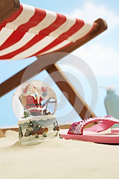 Souvenir santa snow globe under deckchair on beach close up