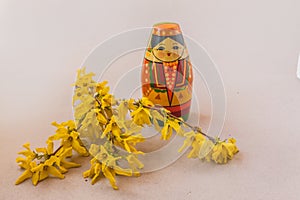 Souvenir stylized as a Tatar girl next to flowering branches of forsythia on a gray background. Mass production. Navruz holiday