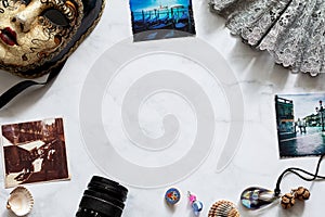 Souvenirs brought from Venice and photographs from trip on light marble table. Moodboard for traveler. Flat lay. Top view