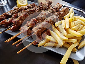 Souvlaki or souvlakia greek ethnic food from roasted meat plate with potatoes and lemon