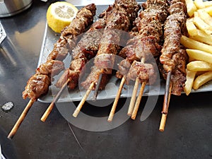 Souvlaki or souvlakia greek ethnic food from roasted meat plate with potatoes and lemon