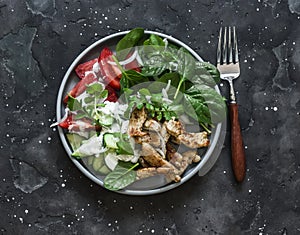 Souvlaki turkey, fresh vegetables salad on a dark background, top view