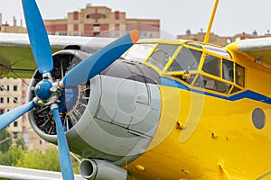 Soviet aircraft biplane Antonov AN-2 with blue four blade propeller and yellow fuselage closeup