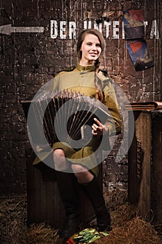 Soviet female soldier in uniform of World War II with an accordion