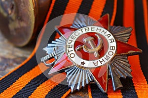 Soviet order of Patriotic War inscription Patriotic war with St. George`s ribbon and empty shell casings on an old wooden table