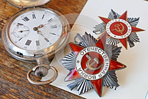 Soviet order of Patriotic war inscription Patriotic war with vintage pocket chronometer on an old wooden table. May 9 Victory da