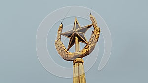 Soviet symbol, golden spire on a cloudy sky background. Stock footage. Golden star and ears of wheat.