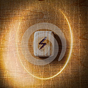 Sowilo. Handmade scandinavian wooden runes on a wooden vintage background in a circle of light. Concept of fortune