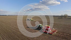 Sowing campaign in early spring. Three tractors pull seeders, aerial 4K video