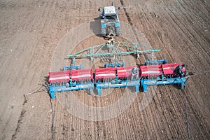 Sowing campaign. The tractor sows the field with grain. There are two seeders sitting on the planter. Shooting from a drone. Copy photo