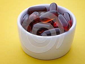 Soy lecithin softgels in a white bowl on a yellow background