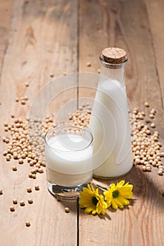 Soy milk or soya milk and soy beans in spoon on wooden table.