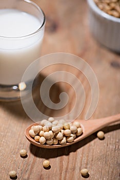 Soy milk or soya milk and soy beans in spoon on wooden table.