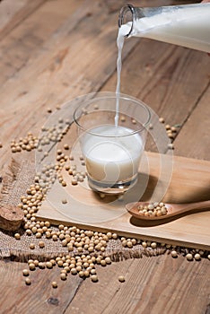 Soy milk or soya milk and soy beans in spoon on wooden table.