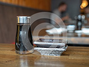 Soy sauce container and stack of dishes in a restaurant with diners