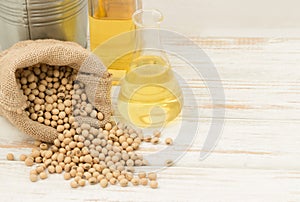 Soybean in hemp sack bag with oil in laboratory glass setup on wooden table.