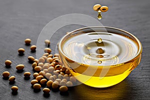 soybean oil dripping from beans in bowl and soy seeds on black stone background