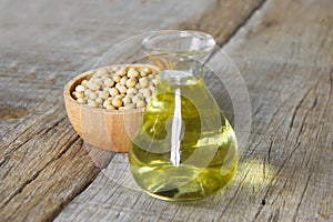 Soybean oil in glass jar and soybean on the woonden background