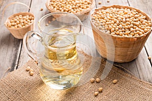 Soybean and soybean oil in jar on wood