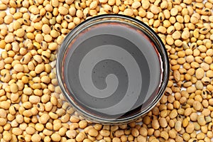 Soybeans background with soy souce in glass bowl. top view