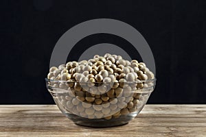 Soybeans on the glass bowl with black and woooden table background