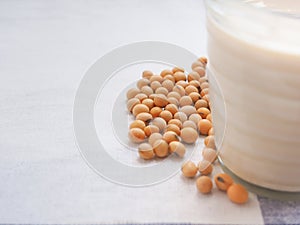 Soybeans and glass of soymilk on a white fabric background.