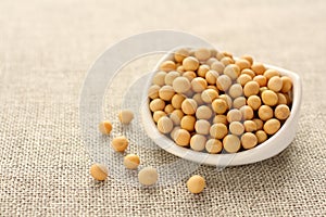 Soybeans in white ceramic bowl on sackcloth background photo