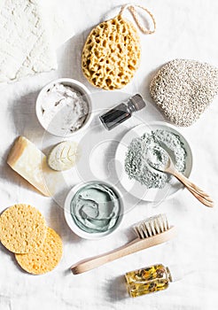 Spa accessories - nut scrub, sponge, facial brush, natural soap, clay face mask, pumice stone, essential oil on a light background