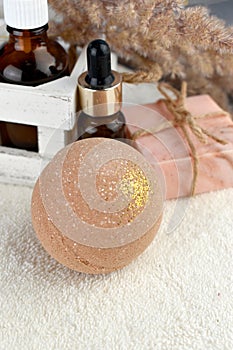 Spa aroma set with bath bombs, essential oil bottle and soap bar on towel.
