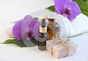 Spa aromatherapy bathe still life composition. Essential oil bottle, dropper, soap bar and orchid over light background.