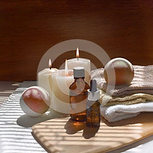 Spa aromatherapy concept with aroma oil bottle, bath bombs, towels and lit candles.