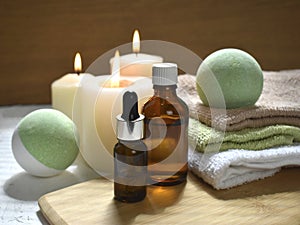 Spa aromatherapy still life with bath bombs, essential oil bottles and lit candles on wooden background.