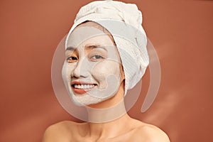 Spa Asian girl applying facial clay mask. Beauty treatments. Over blue background