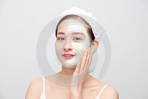 Spa Asian Woman applying Facial clay Mask over white background. Beauty Treatments