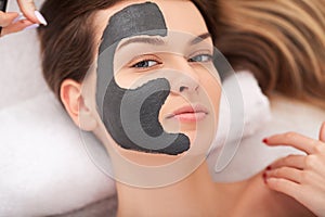 Spa. Attractive funny woman with a clay mask on her face.