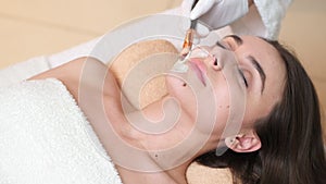 Spa. Attractive funny woman with a clay mask on her face.