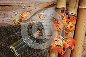 Spa background with bamboo, bath salt, massage oil, autumn leaves and towel