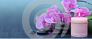 Spa background with pink orchid , candle and zen black stones on gray.