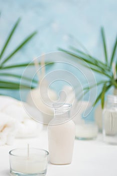 Spa background: thai massage bag, cosmetics, towels and palm leaves on blue background. Healthy lifestyle