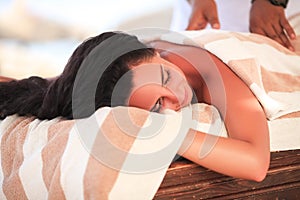 Spa. Beautiful woman get massage on sunny beach. Relax on vacations.